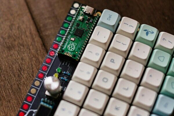 Raspberry Pi Pico and mechanical keyboard close-up on wooden surface