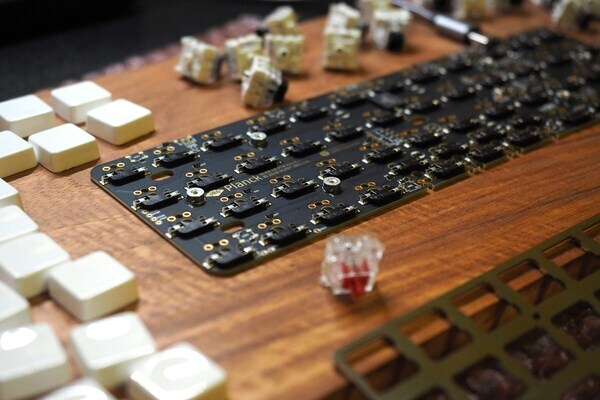 Planck keyboard PCB with keycaps and switches on wooden surface, custom keyboard PCB build