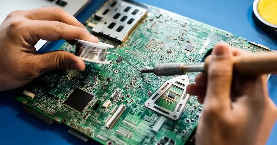 Technician soldering PCB circuit board with soldering iron and solder wire