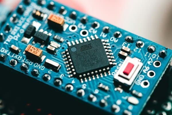 ATmega328P microcontroller IC soldered on blue Arduino PCB with electronic components